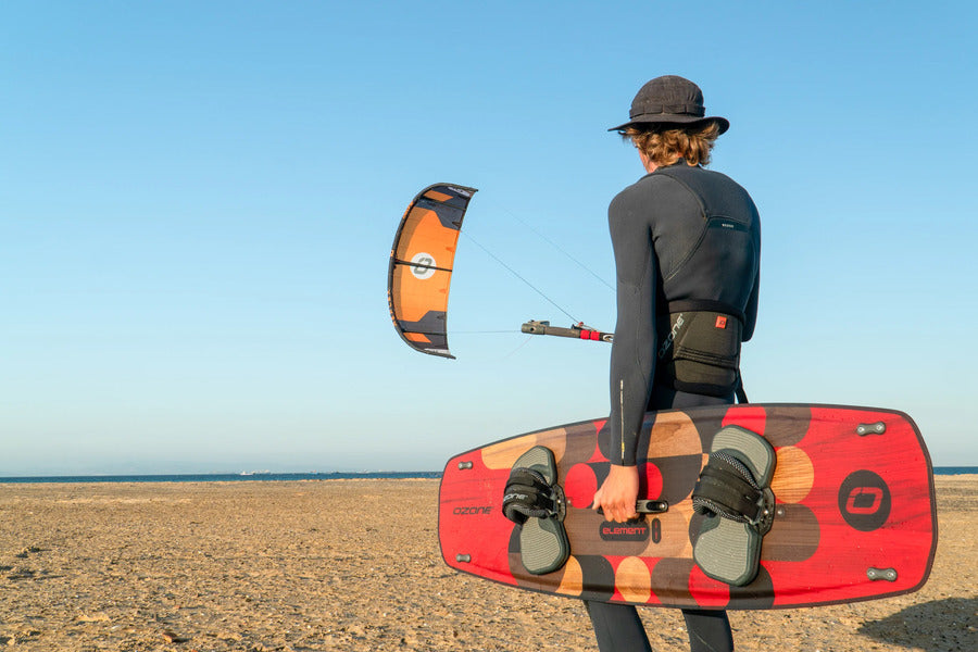 Ozone Element kiteboard Ireland - rider carrying the new Element twin tip on the beach with an Ozone kite